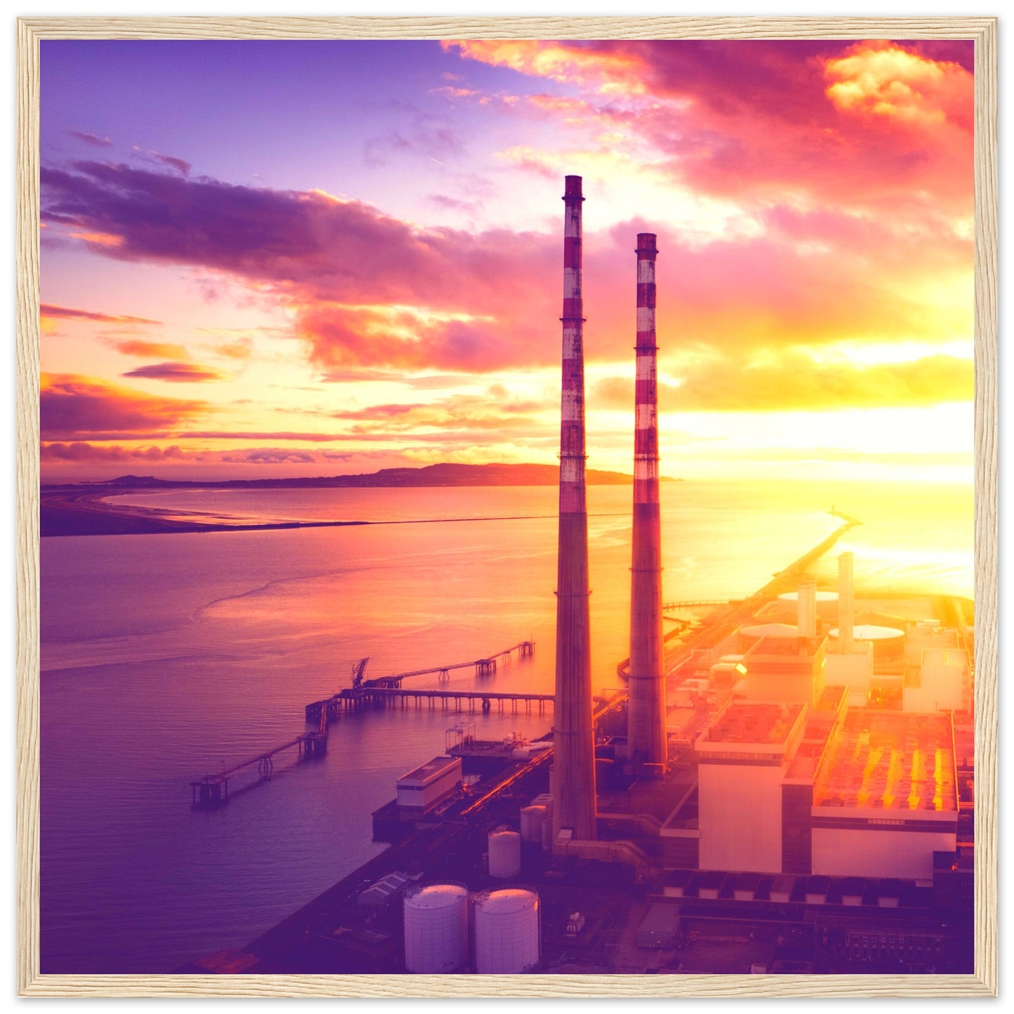 A framed print of Dublin's industrial landscape, featuring the iconic Poolbeg Towers and Lighthouse at sunrise. This aerial view captures the blend of industrial structures with a serene, sunlit horizon, showcasing the harmony between technology and nature. Perfect for admirers of drone photography, industrial architecture, and Ireland's coastal beauty.