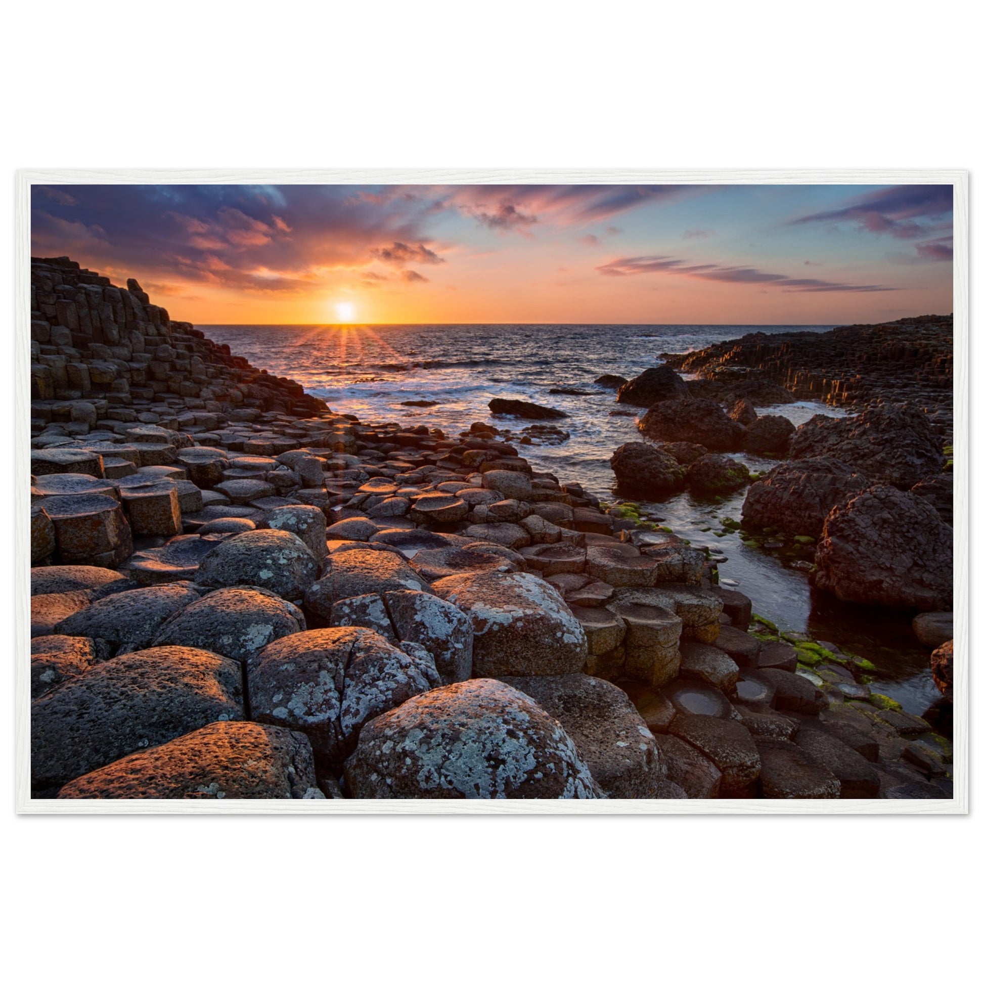 Framed art print of a mesmerizing sunset at Giant's Causeway, featuring iconic basalt columns under a sky painted with warm hues. Captures nature's beauty and tranquility, adding a sophisticated touch to any home or office decor. Ideal for art enthusiasts.