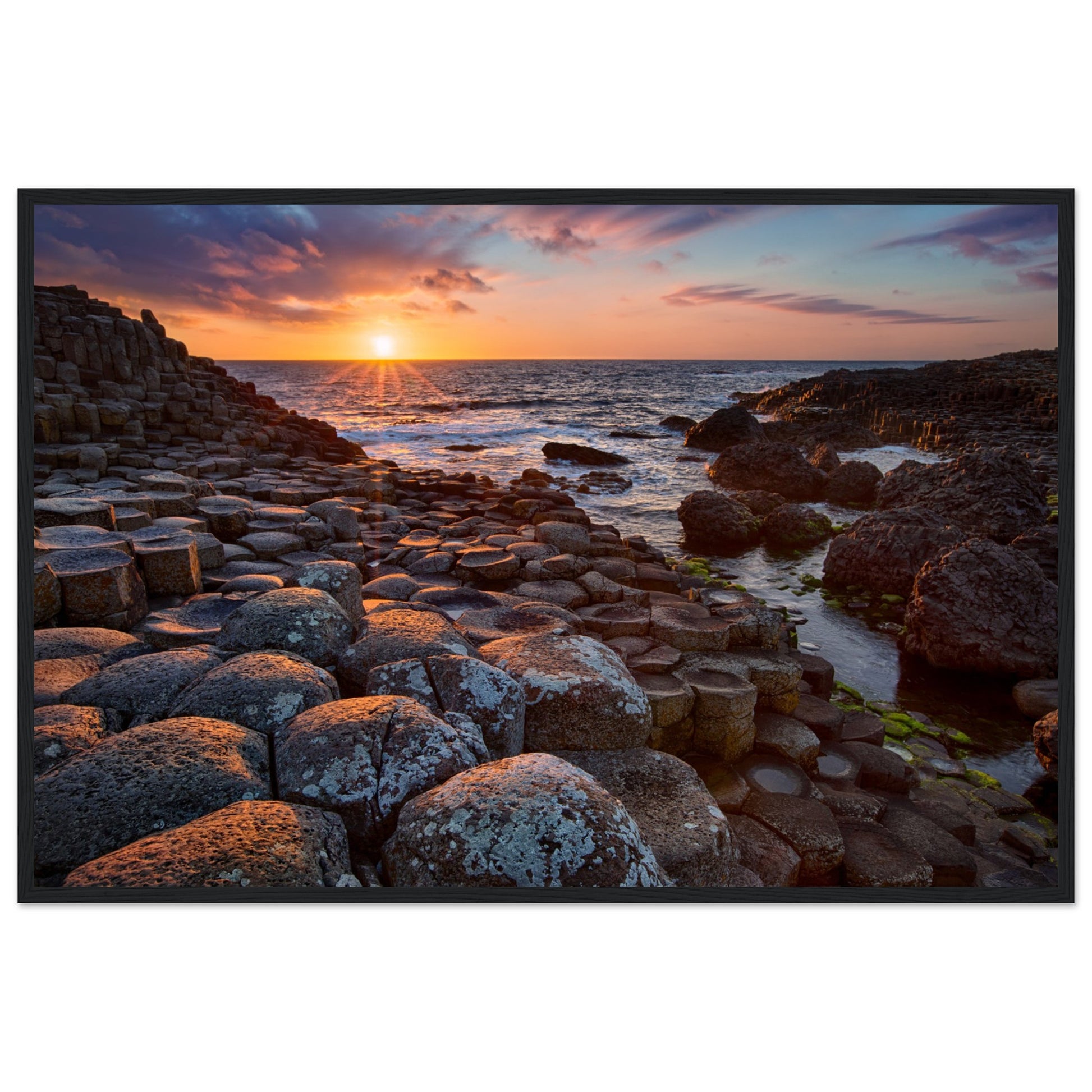 Framed art print of a mesmerizing sunset at Giant's Causeway, featuring iconic basalt columns under a sky painted with warm hues. Captures nature's beauty and tranquility, adding a sophisticated touch to any home or office decor. Ideal for art enthusiasts.